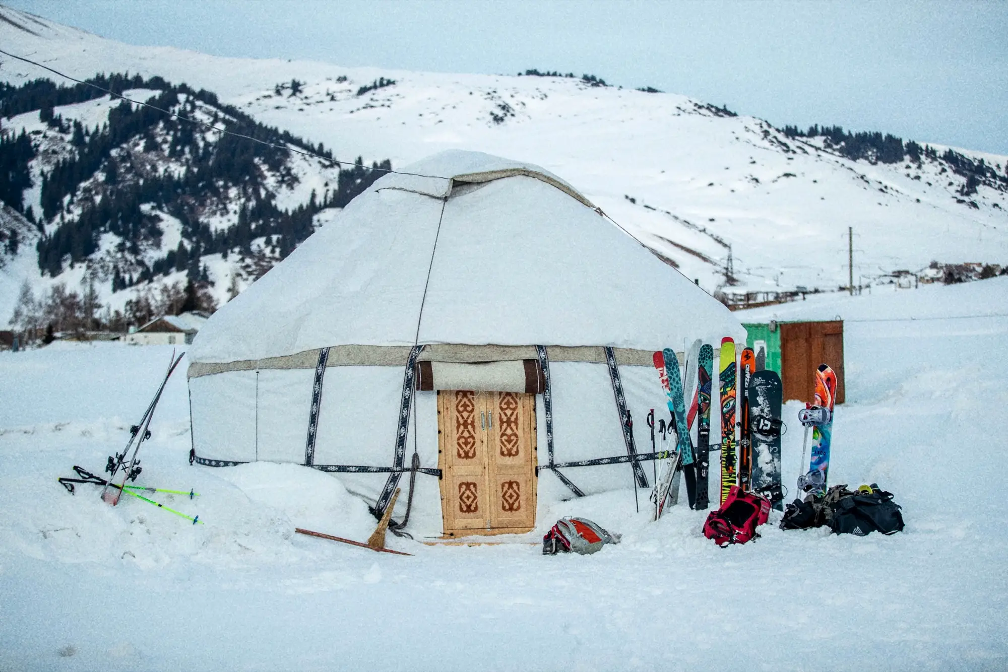 Yurt in de sneeuw in Kirgizië, met ski's en snowboards tegen de wand